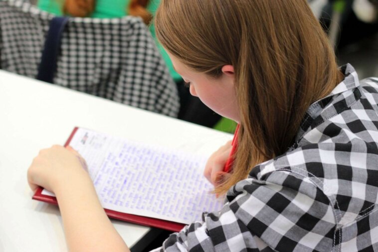 jovem com cadernos estudando adjetivos