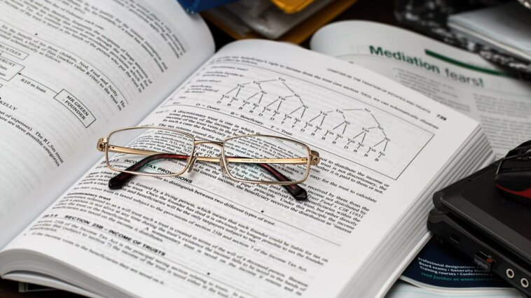 óculos sobre livro de matemática que explica conceitos de fatoração